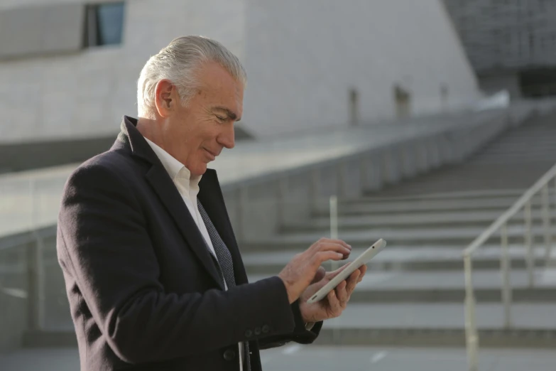 a man in a suit looks at soing on his tablet