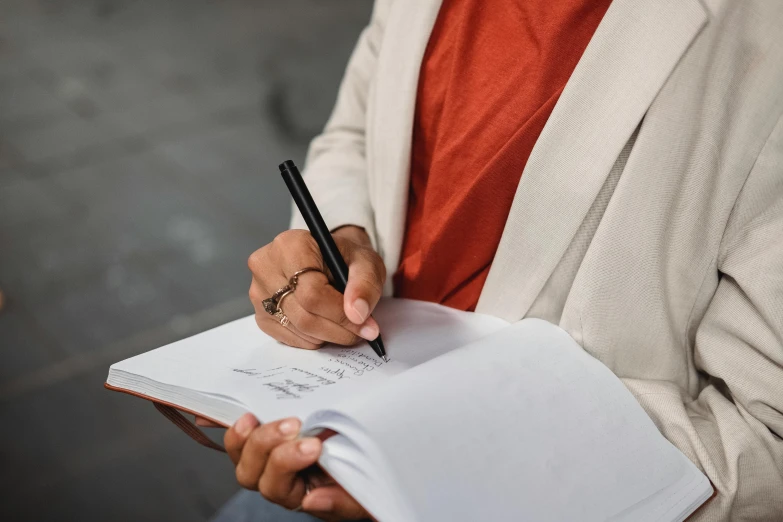 a person in a white suit is writing on an open notebook