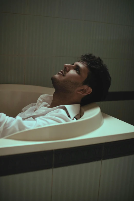 a man laying down in a bathtub next to a sink