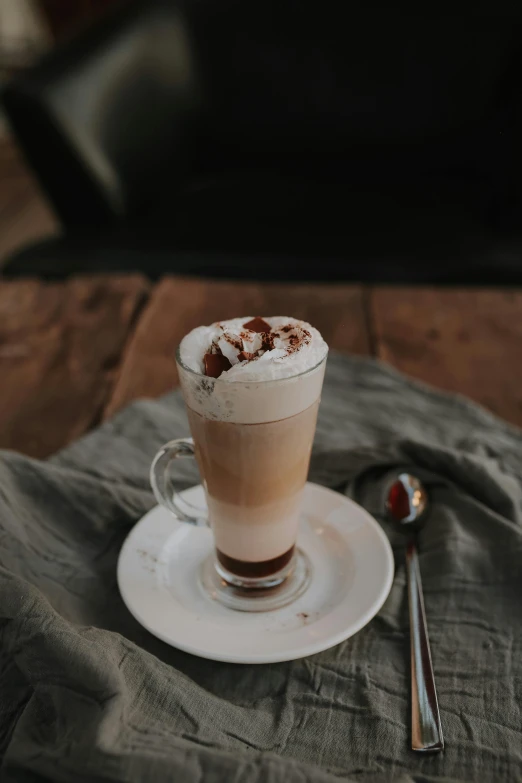 a drink with ice sits on a saucer with a spoon