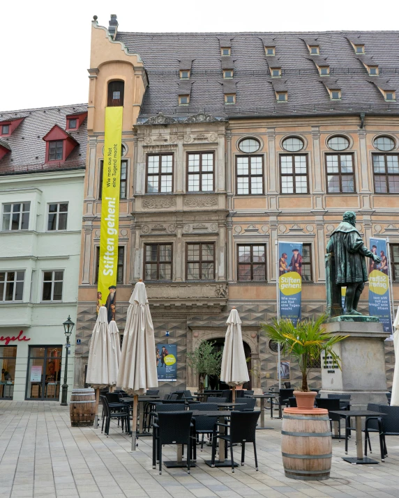 a courtyard with tables, umbrellas, chairs and a building