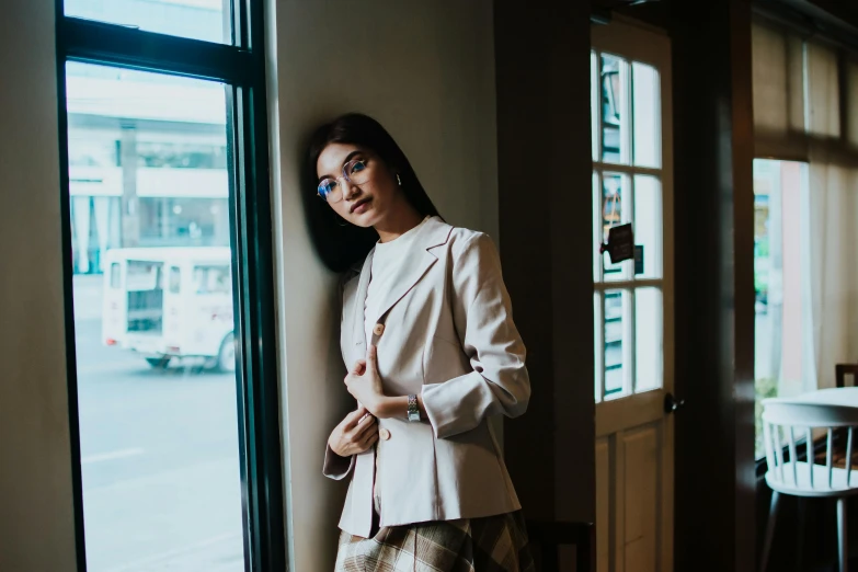 a girl in a business suit leaning against a wall