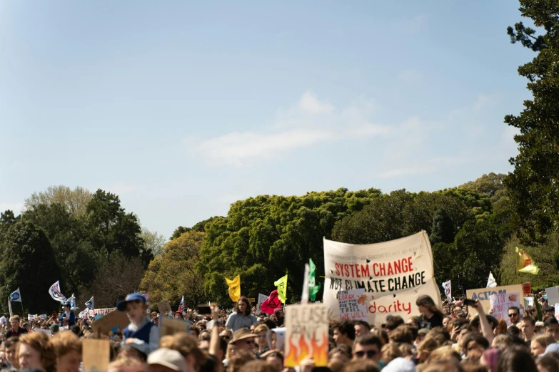 a large crowd is protesting a climate change campaign