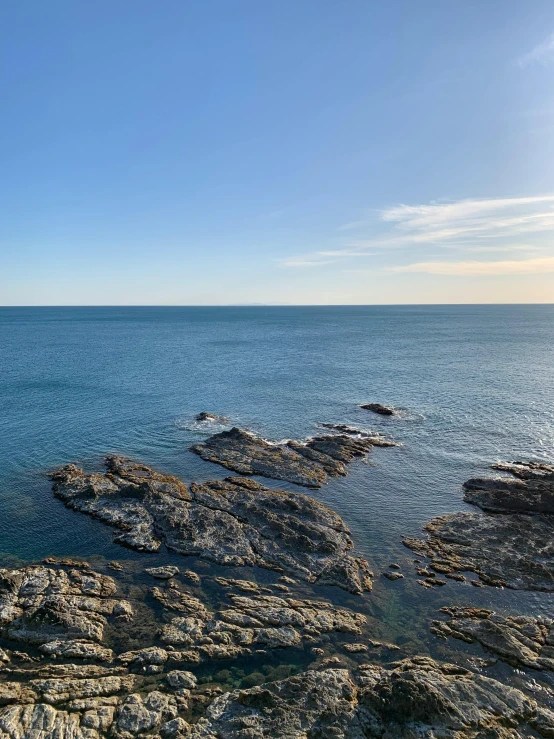 a rock covered coast with an ocean and clear sky