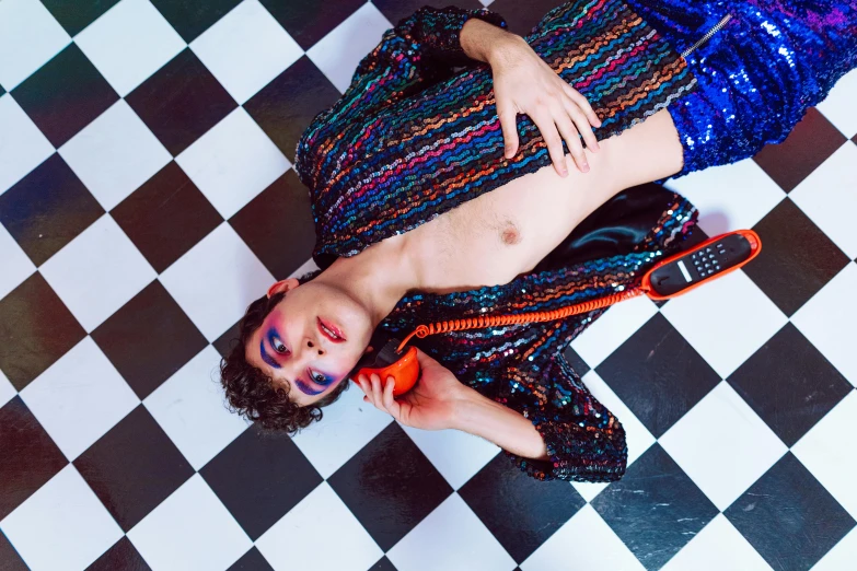 a man sitting on top of a floor holding an orange cellphone