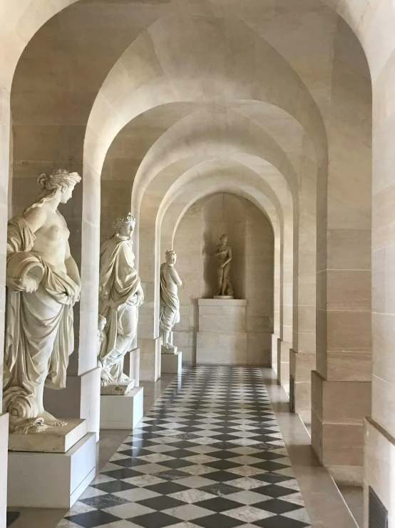 statues lined up at the end of a white hallway