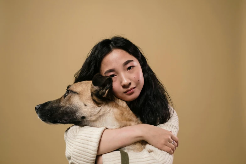 an asian woman hugging a dog in her arms