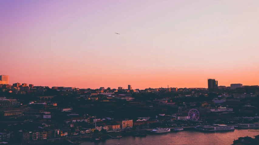 a city at sunset overlooking the water with airplanes flying by