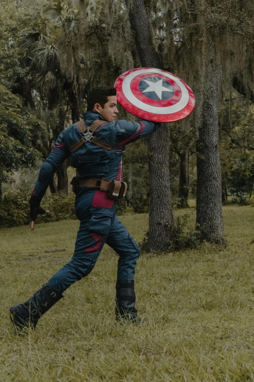 a man is holding a large shield in the park