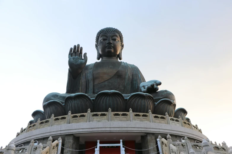 the large buddha statue in front of a red wall