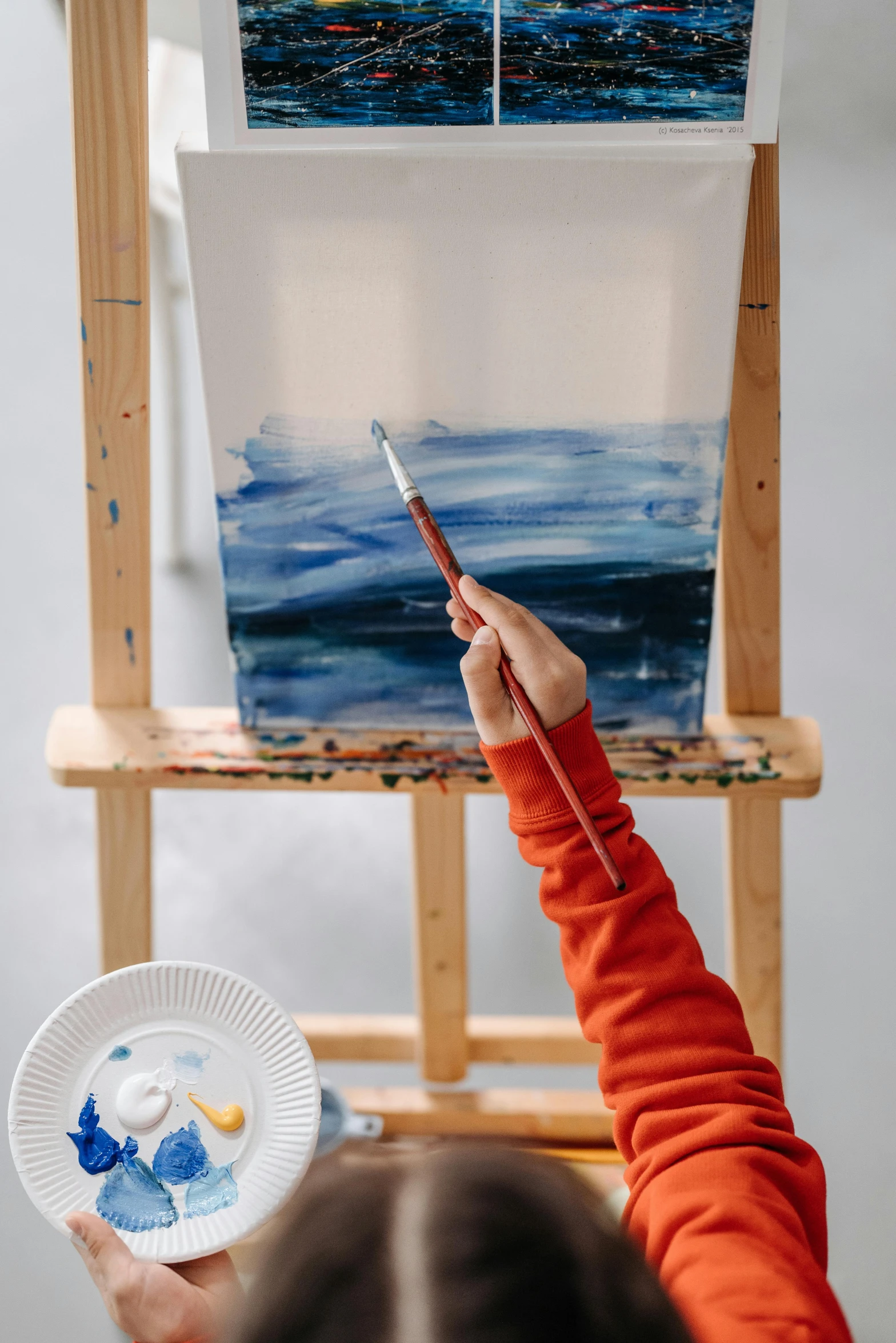 woman holding a paintbrush painting an ocean scene