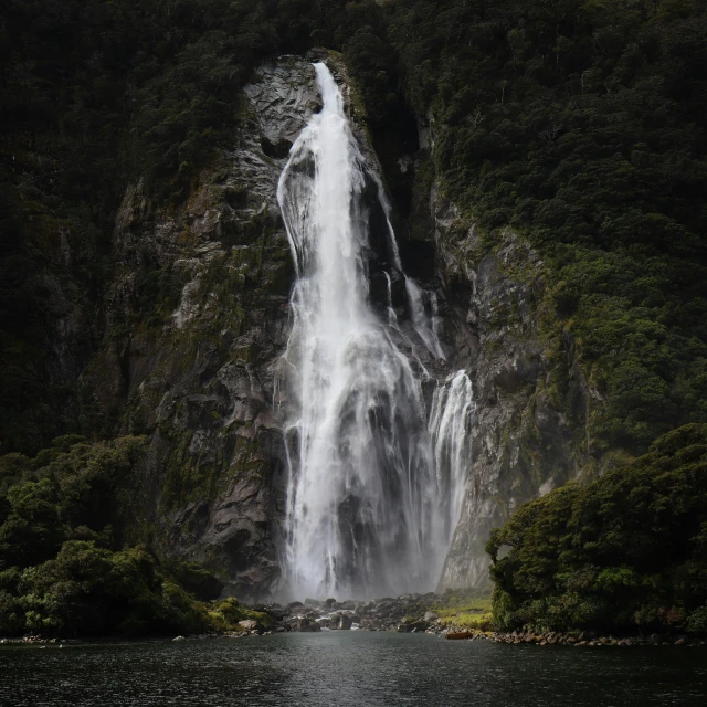 a large waterfall is located by a mountain