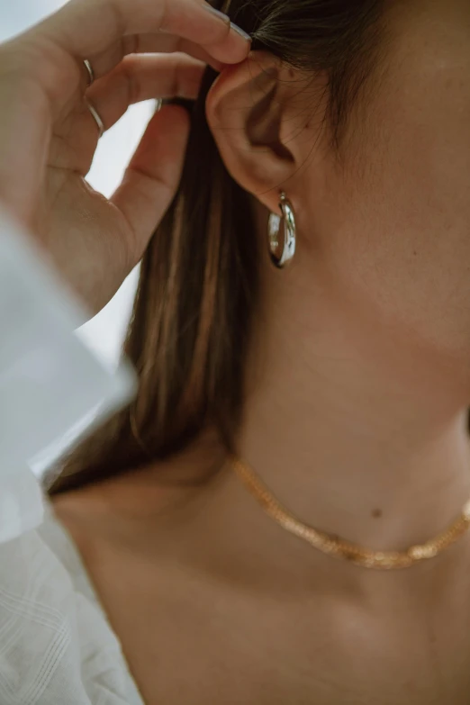 a woman holds her ear up to her nose