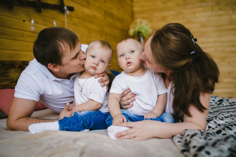 a family laying on a bed with their little babies