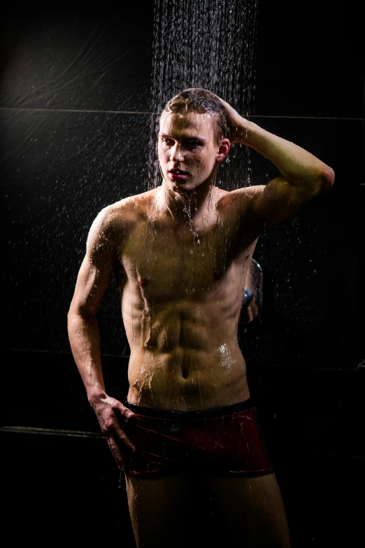 a man standing under a shower holding his head