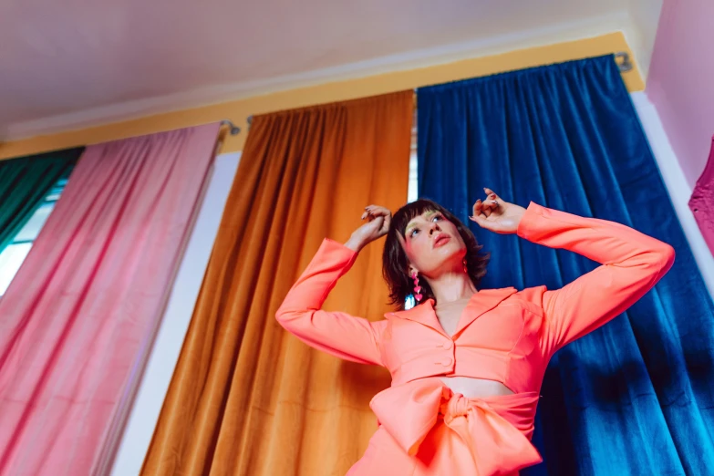 a woman in an orange dress standing in front of a window