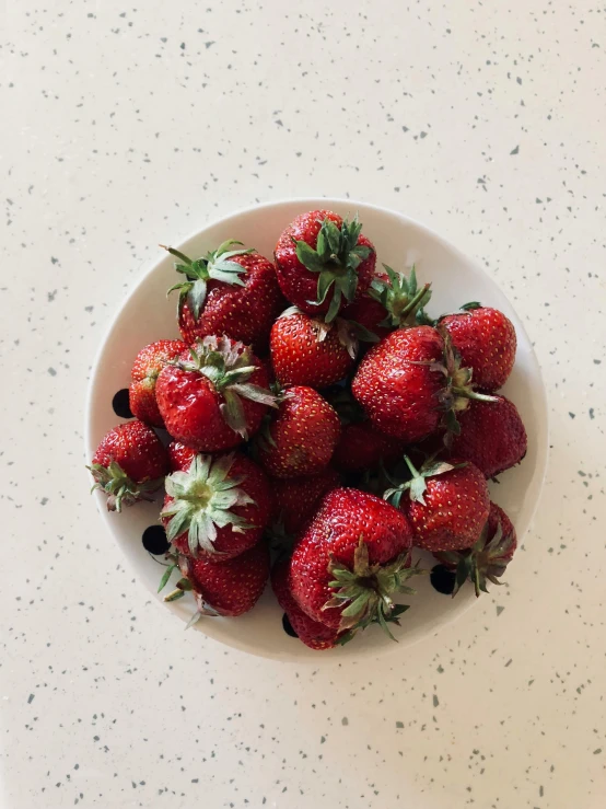 small bowl full of strawberries on table top