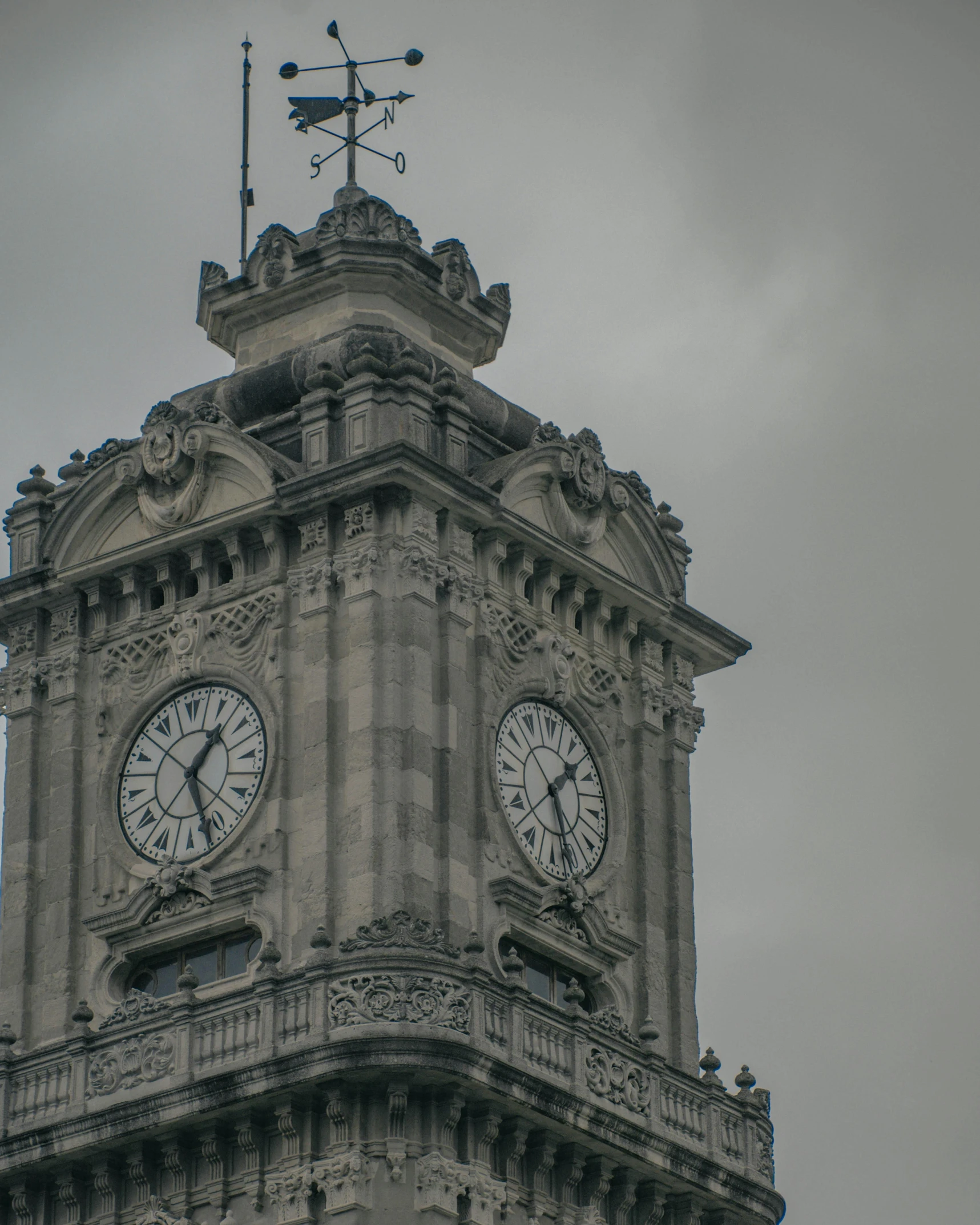 a clock tower has ornate architectural designs and weather vane