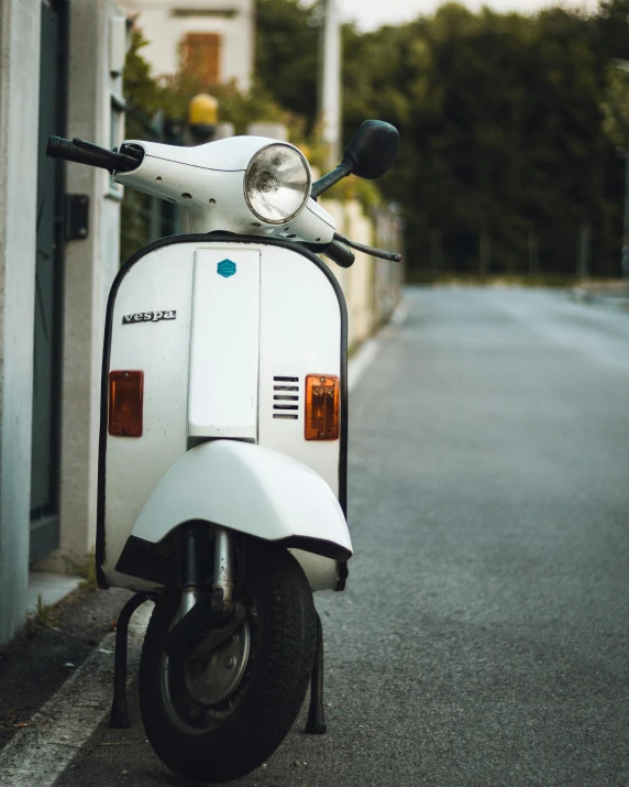 a white scooter parked on the side of the street