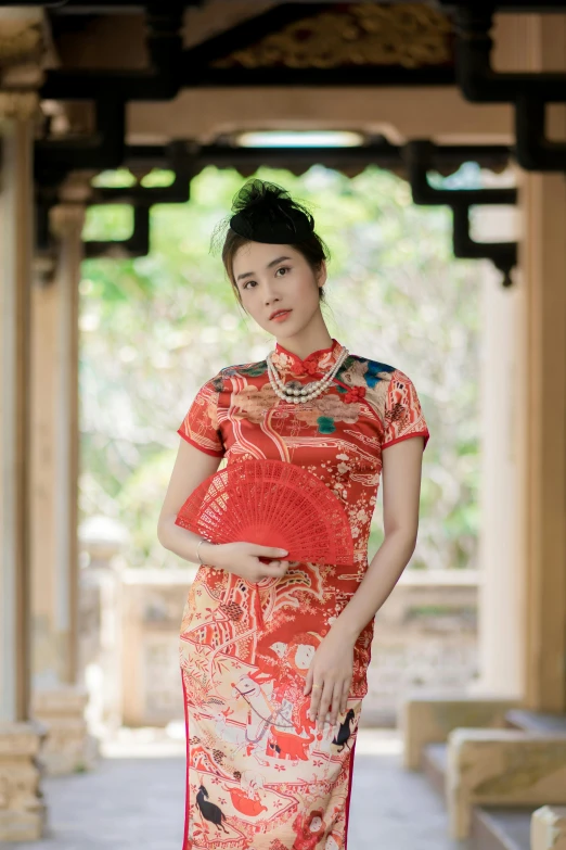 a woman in a red and beige dress posing for the camera