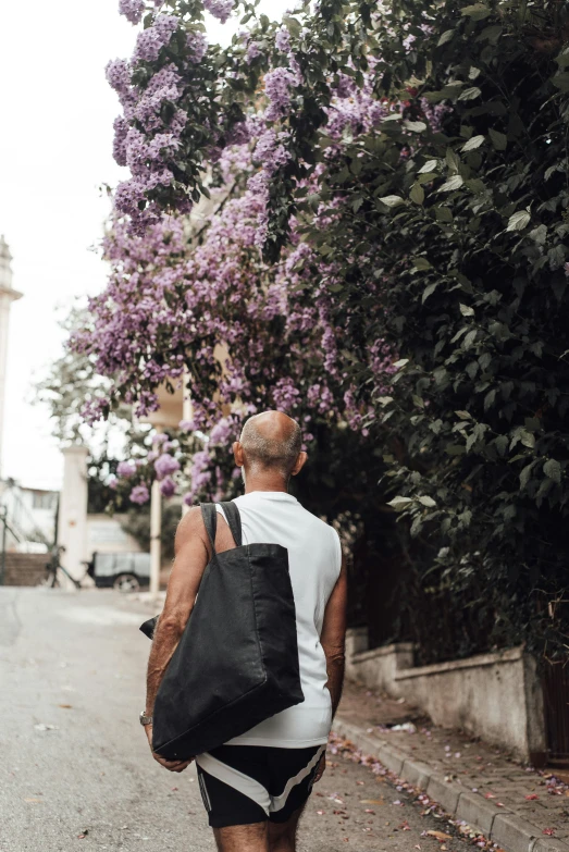 a man walking down a street with a black purse in his hand