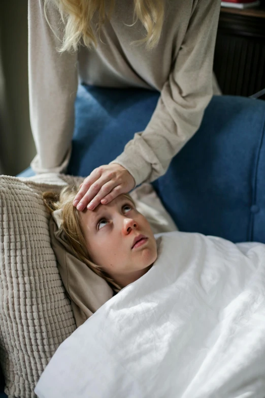 a woman is laying in bed while the lady adjusts her hair