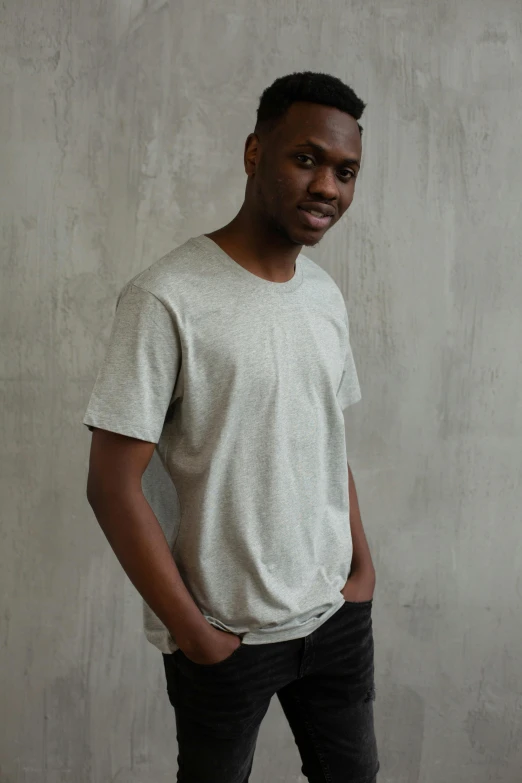 a young man standing up against a wall wearing a white shirt