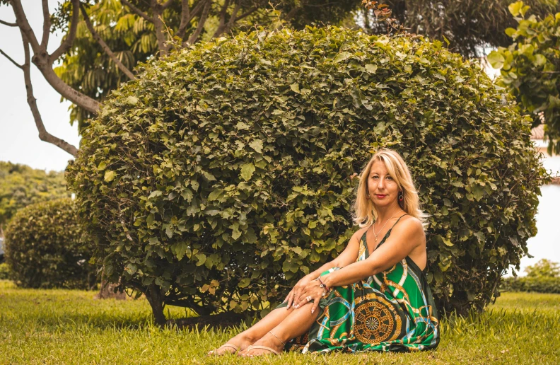 the woman sits in front of a hedge