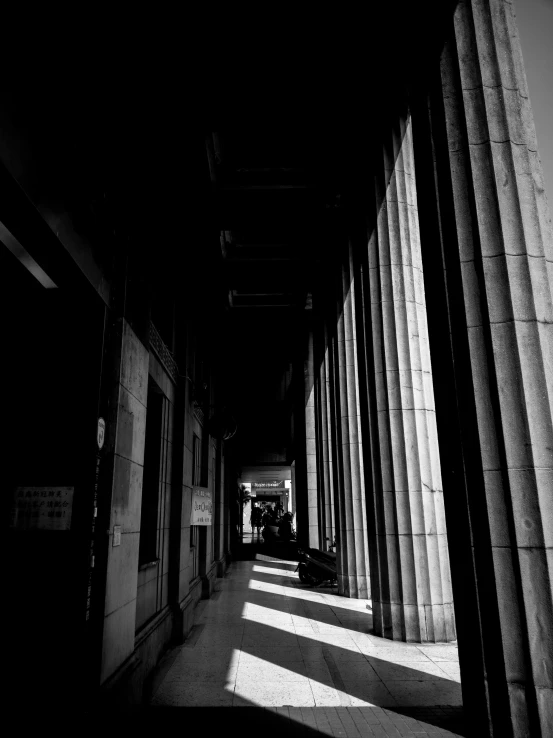 an empty hallway with rows of columns and people standing on it