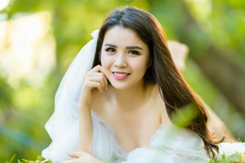 an asian woman in a wedding dress posing on some grass