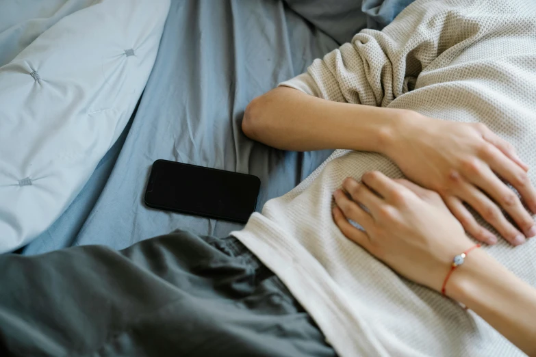 a person has their hands together while laying on a bed