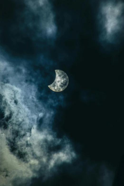 the moon is in the clouds against a dark sky