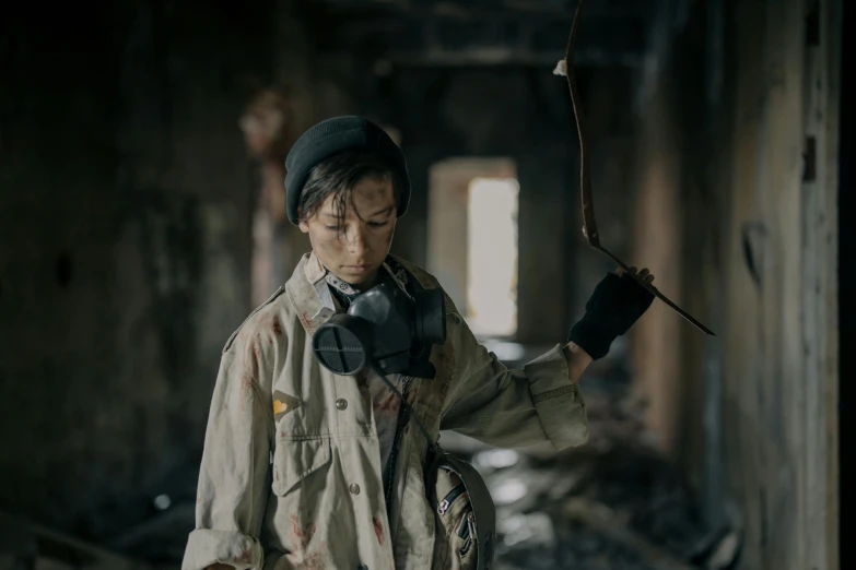 woman with gas mask walking through ruins and holding long stick