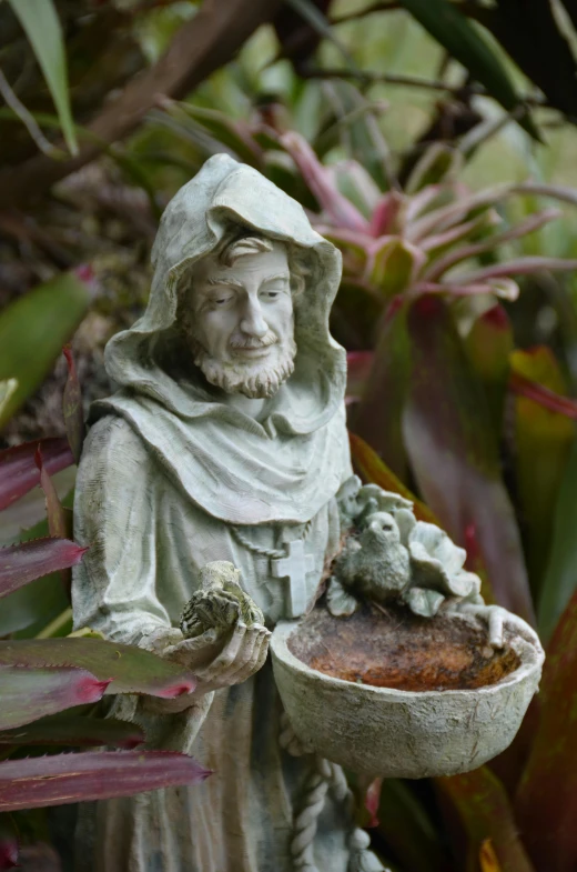 a statue of the monk is holding a bird bowl