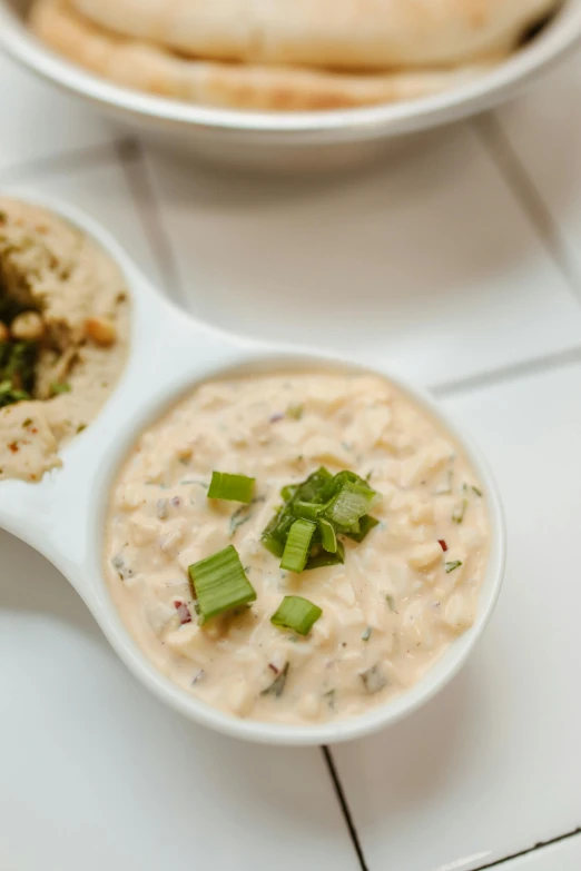 an appetizer set in a bowl with dip and pita bread on the side