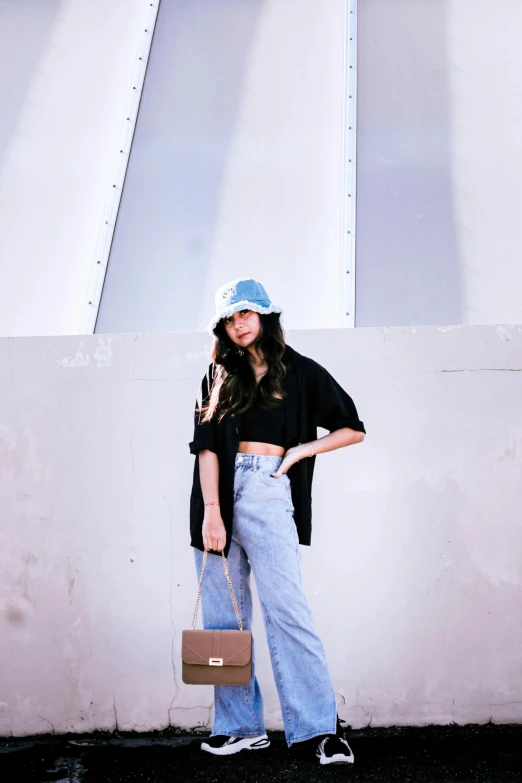 a woman holding a brown handbag next to white wall