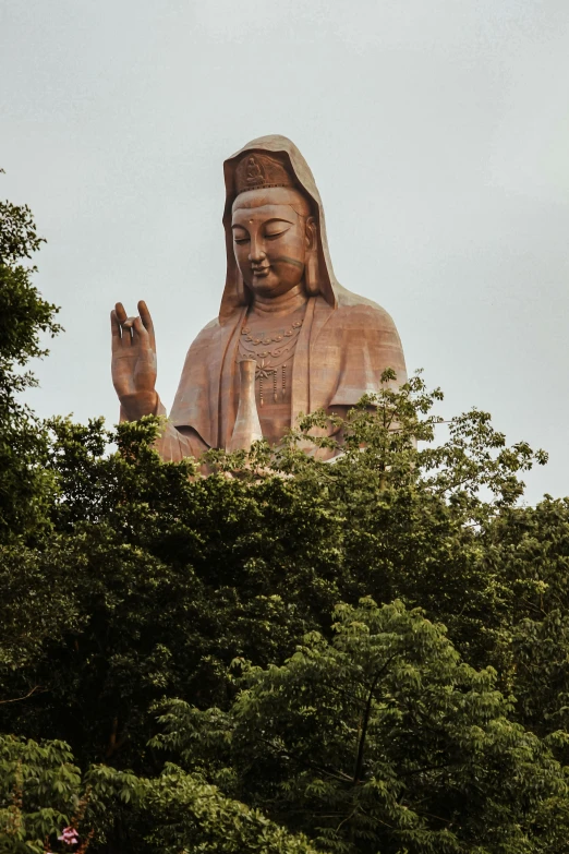 a giant buddha statue sitting on top of a green hillside