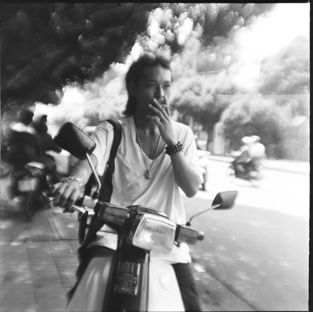 black and white pograph of a man smoking on his moped