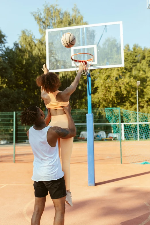 people playing basketball on a court in the sun