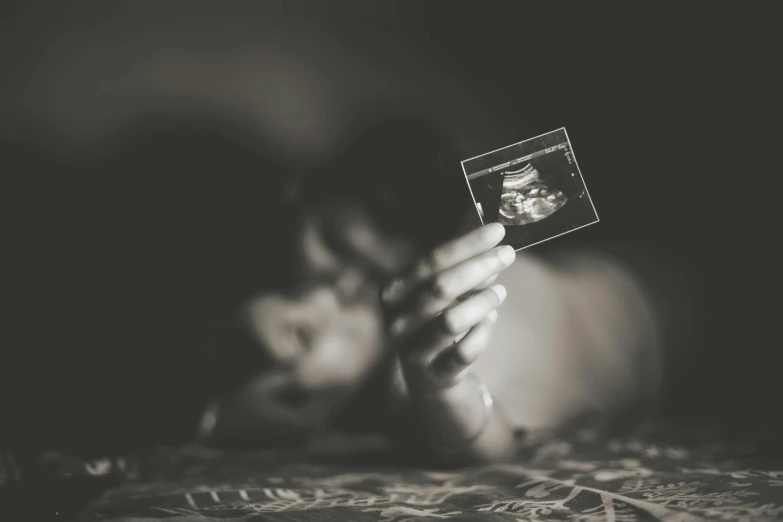 a woman holding a small polaroid with a picture