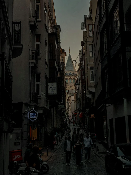 dark, narrow street with buildings and pedestrians