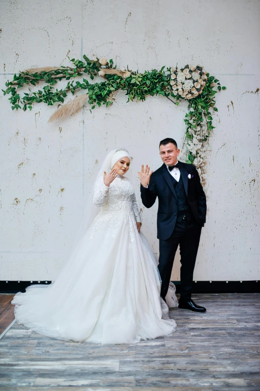 a bride and groom pose next to an artistic backdrop