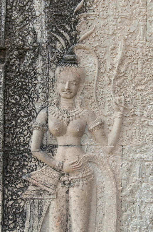 a stone carving of a female holding a pot