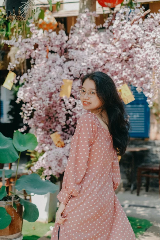 the girl is posing under a flowering tree