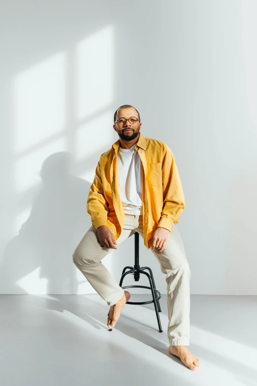 an older man sitting on a chair, with a bright window behind him