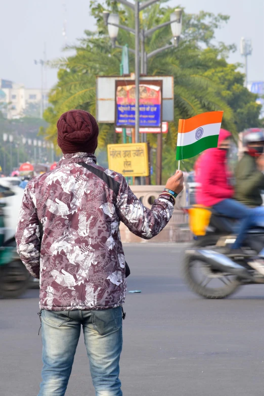 the man is carrying an indian flag on a scooter