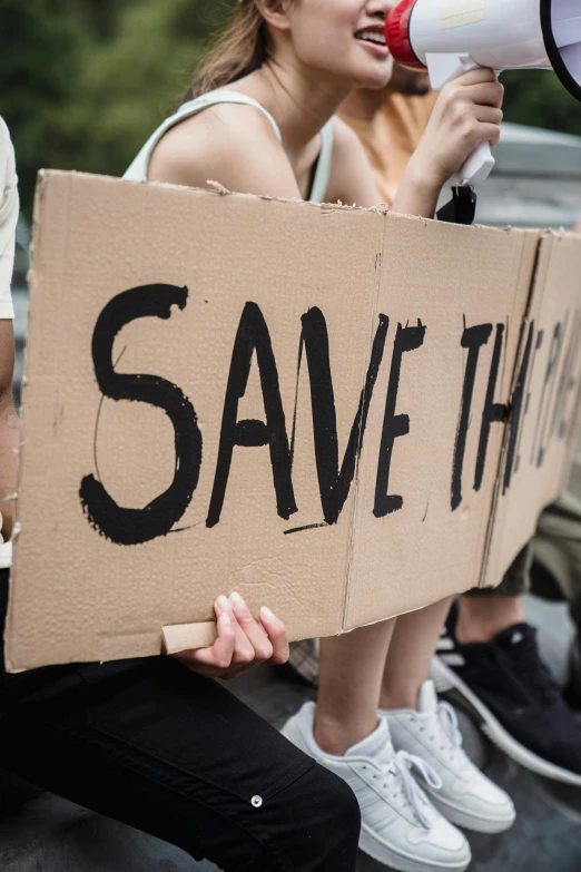 a woman holding a protest sign and a megaphone in her hands