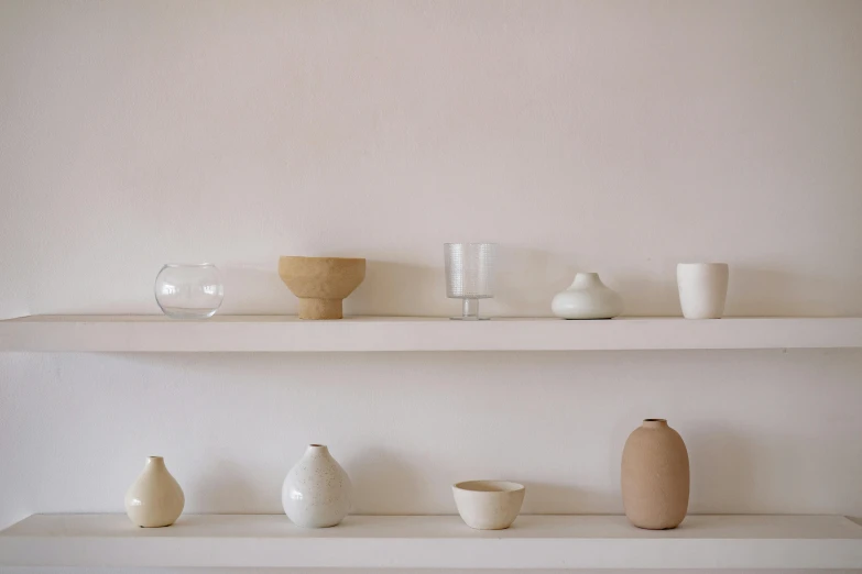 a white shelf with vases on top of it