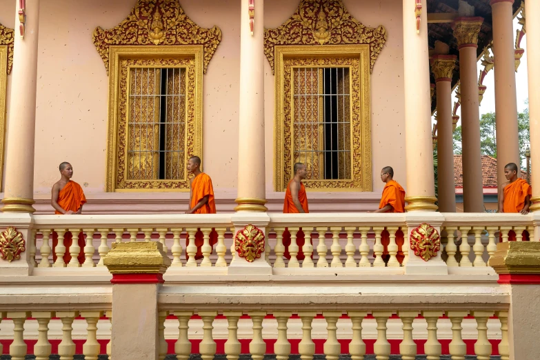 three monks in orange robes are on the balcony