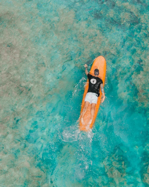 the view from the air shows an overhead view of someone paddling a kayak over shallow blue water